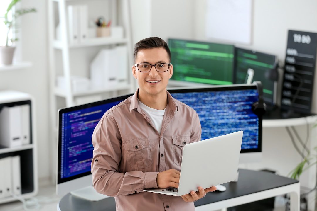 IT support technician working at a computer in a modern office, providing remote help desk assistance.